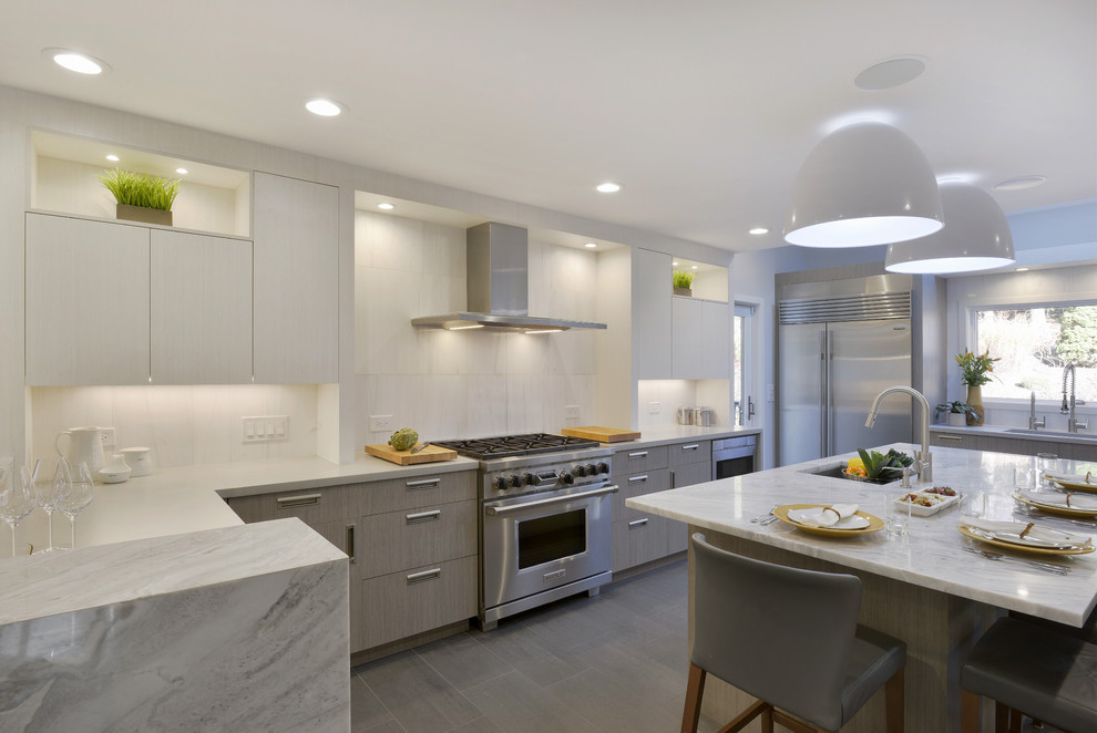 Design ideas for a large modern l-shaped open plan kitchen in New York with an undermount sink, flat-panel cabinets, grey cabinets, concrete benchtops, white splashback, stone tile splashback, stainless steel appliances, limestone floors and with island.