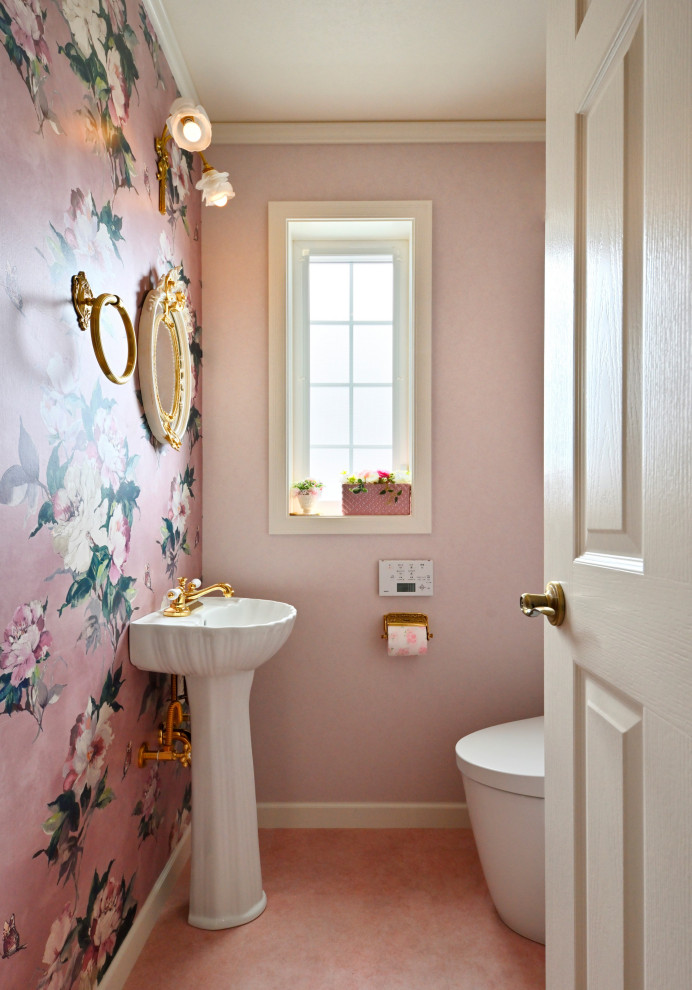 На фото: маленький туалет в классическом стиле с унитазом-моноблоком, розовыми стенами, полом из винила, раковиной с пьедесталом, розовым полом, акцентной стеной, потолком с обоями и обоями на стенах для на участке и в саду с