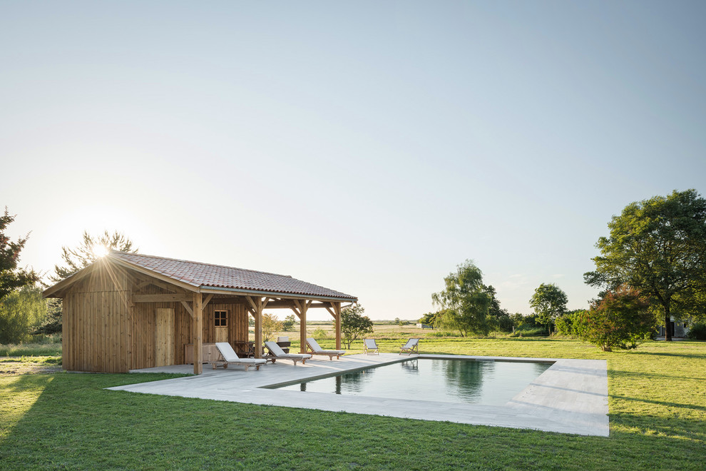 This is an example of a large country rectangular pool in Bordeaux with a pool house and tile.