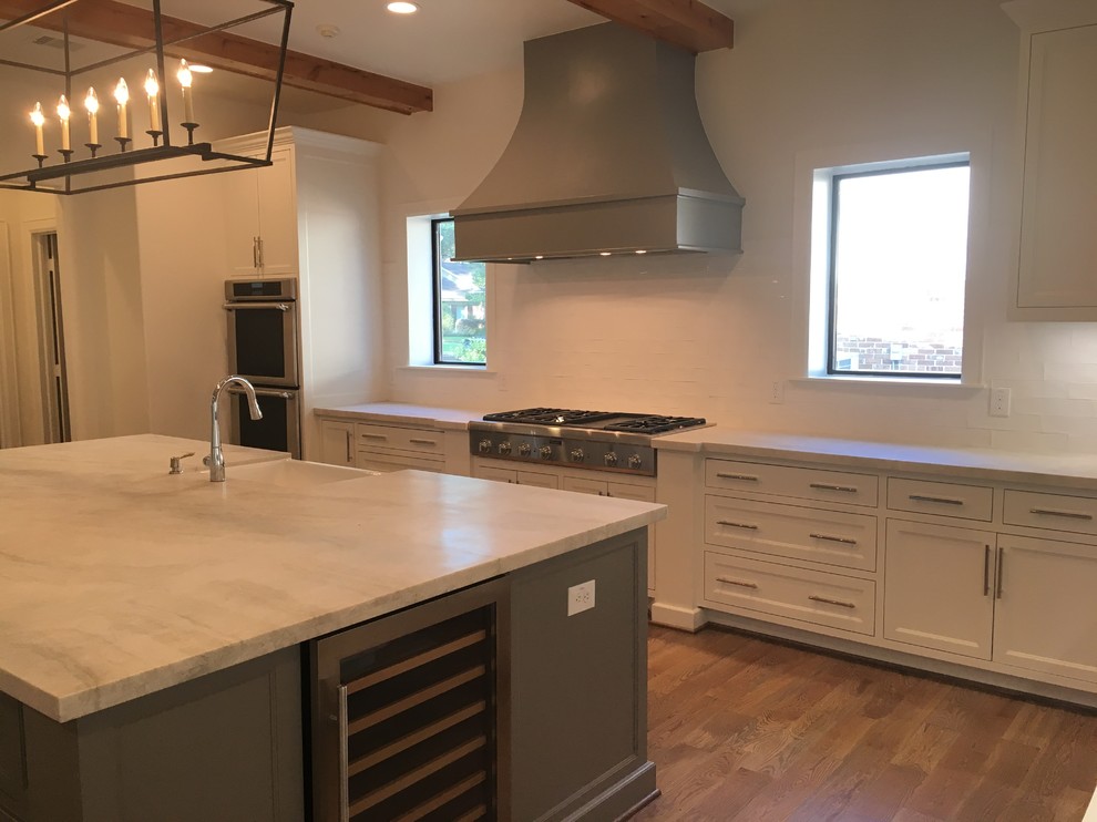 Example of a large transitional u-shaped medium tone wood floor and brown floor open concept kitchen design in Houston with a farmhouse sink, shaker cabinets, white cabinets, wood countertops, white backsplash, subway tile backsplash, stainless steel appliances and an island