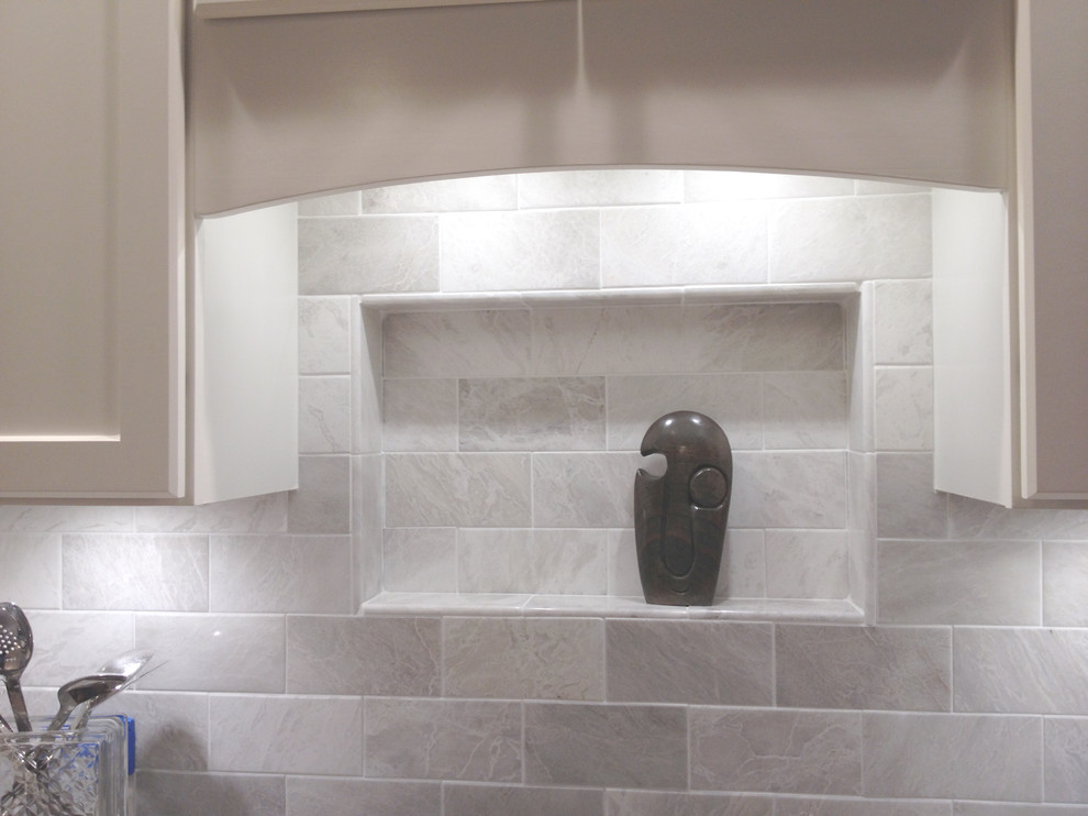 Example of a mid-sized transitional l-shaped light wood floor eat-in kitchen design with an undermount sink, recessed-panel cabinets, white cabinets, granite countertops, white backsplash, stone tile backsplash, white appliances and a peninsula