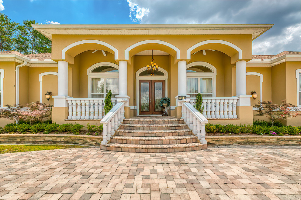 Design ideas for a mediterranean one-storey yellow house exterior in Tampa with a flat roof.