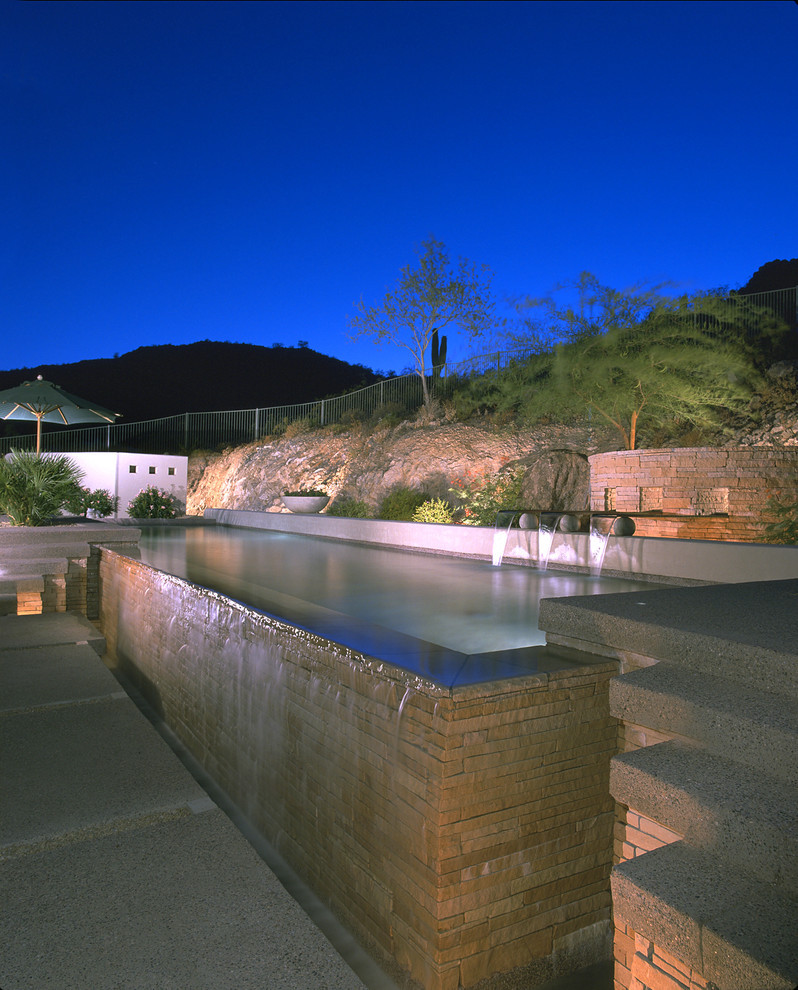 Photo of a transitional backyard rectangular infinity pool in Phoenix with a water feature and decking.