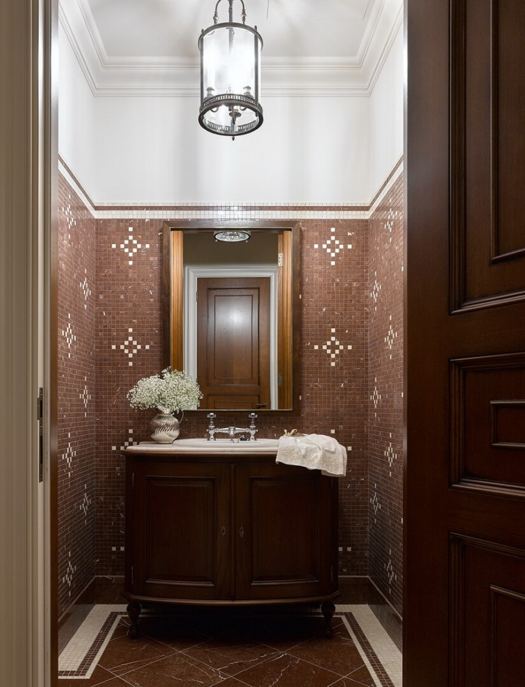 Klassisk inredning av ett mellanstort beige beige toalett, med luckor med upphöjd panel, skåp i mörkt trä, en toalettstol med separat cisternkåpa, brun kakel, marmorkakel, beige väggar, marmorgolv, ett nedsänkt handfat, marmorbänkskiva och brunt golv