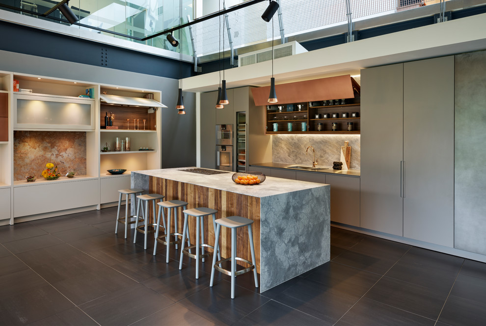 Photo of an expansive contemporary single-wall open plan kitchen in London with flat-panel cabinets, beige cabinets, marble worktops, beige splashback, glass sheet splashback, integrated appliances, ceramic flooring, an island, black floors and grey worktops.