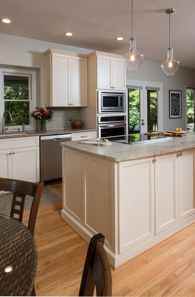 Inspiration for a transitional l-shaped light wood floor eat-in kitchen remodel in Raleigh with an undermount sink, shaker cabinets, blue backsplash, stainless steel appliances and an island