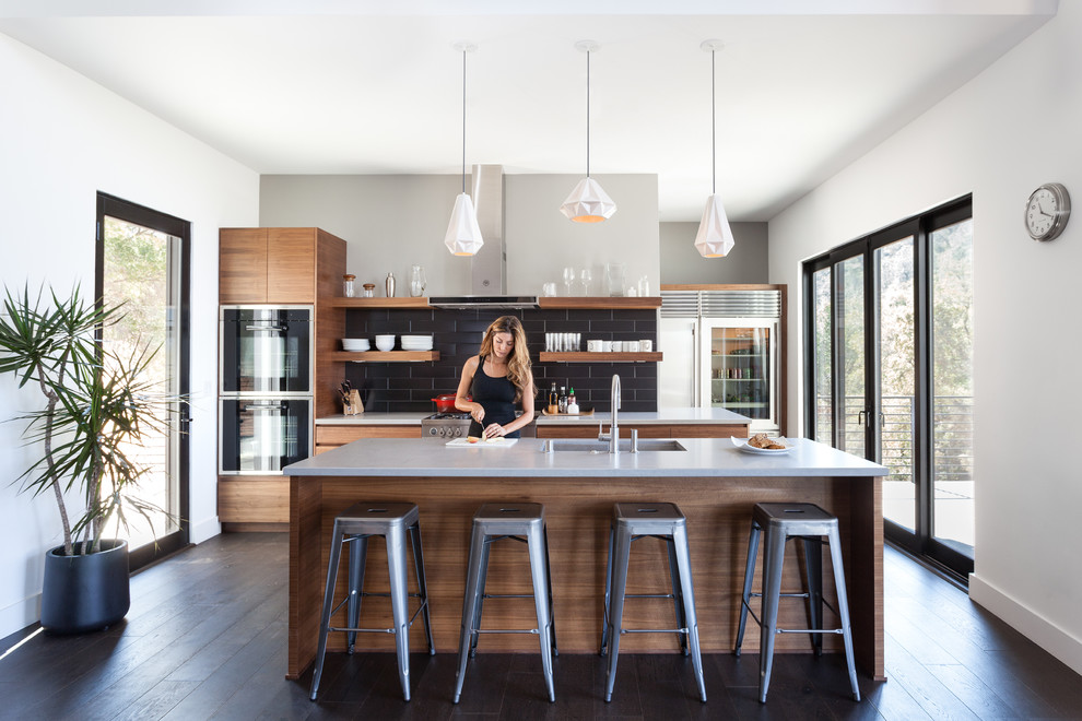 Design ideas for a contemporary galley kitchen in Sacramento with an undermount sink, flat-panel cabinets, medium wood cabinets, black splashback, stainless steel appliances, dark hardwood floors and with island.