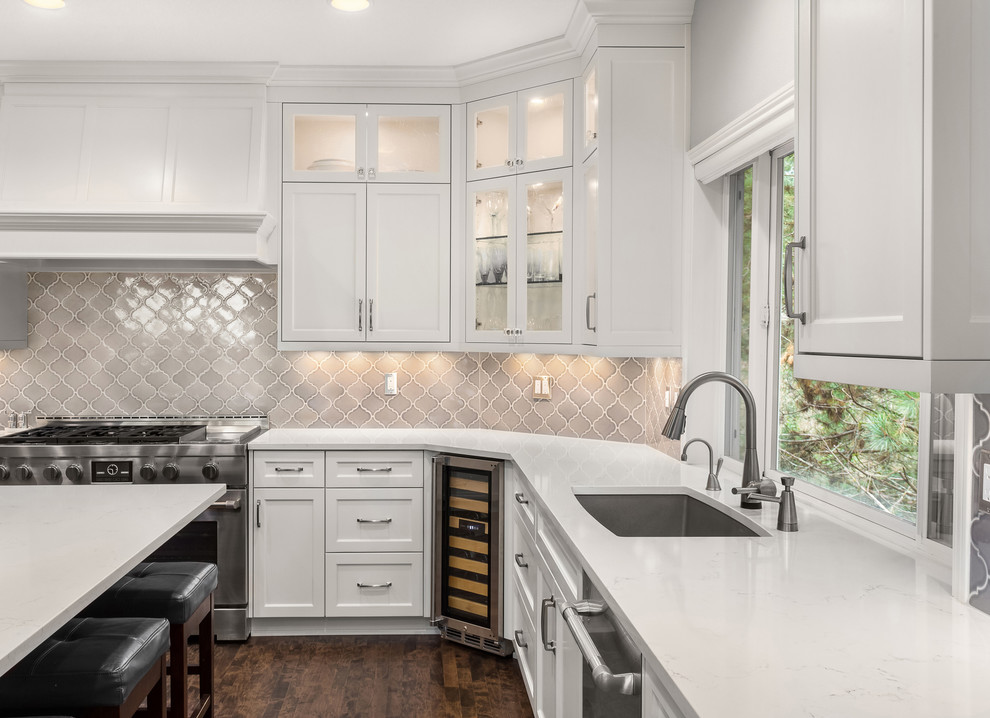 Inspiration for a large transitional u-shaped kitchen in Portland with an undermount sink, shaker cabinets, white cabinets, quartzite benchtops, grey splashback, ceramic splashback, stainless steel appliances, dark hardwood floors, with island, brown floor and white benchtop.