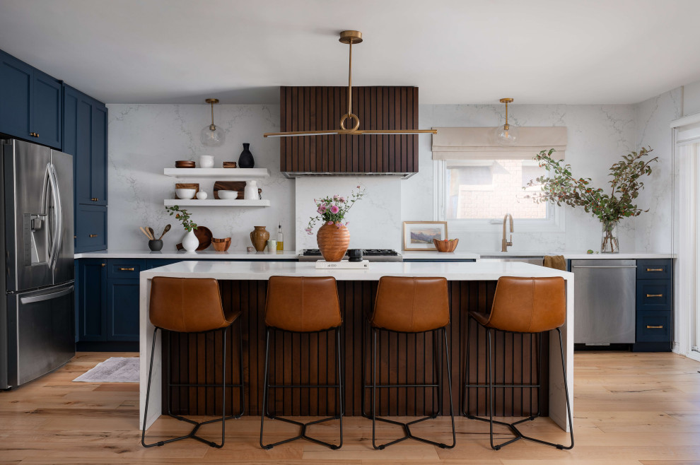 Mid-sized transitional l-shaped medium tone wood floor and beige floor eat-in kitchen photo in Toronto with a farmhouse sink, shaker cabinets, blue cabinets, quartz countertops, white backsplash, quartz backsplash, stainless steel appliances, an island and white countertops