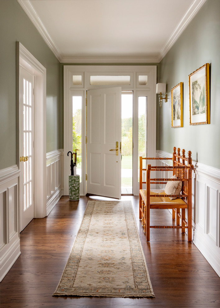 Large country medium tone wood floor, brown floor and wainscoting front door photo in Milwaukee with green walls and a white front door