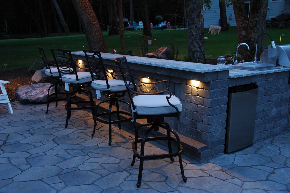 Photo of a mid-sized traditional backyard patio in Minneapolis with an outdoor kitchen, natural stone pavers and no cover.
