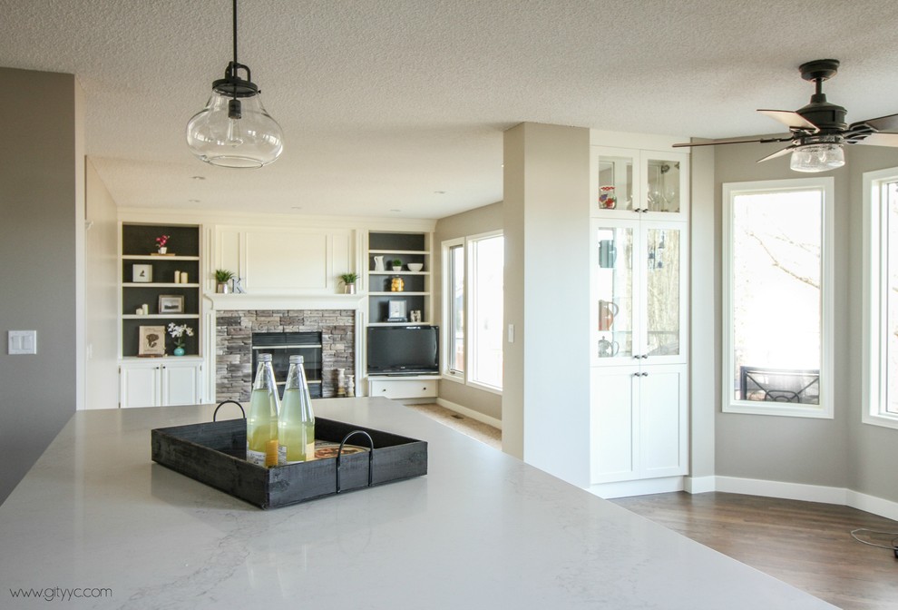 This is an example of a large transitional u-shaped eat-in kitchen in Calgary with an undermount sink, shaker cabinets, white cabinets, quartzite benchtops, white splashback, ceramic splashback, stainless steel appliances, medium hardwood floors and with island.