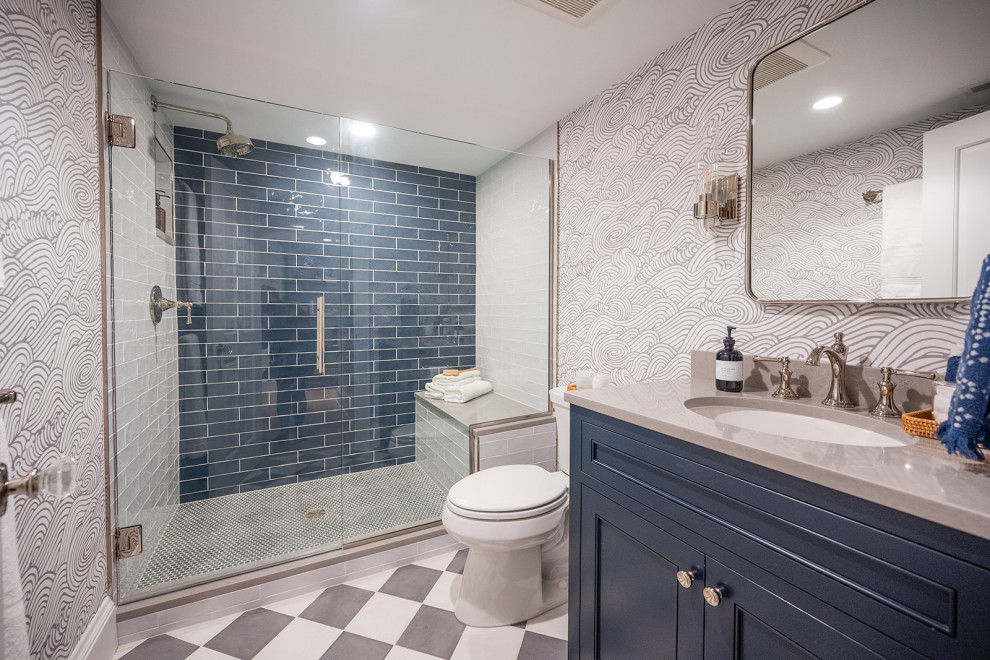 3/4 bathroom in Minneapolis with blue cabinets, blue tile, porcelain tile, porcelain floors, an undermount sink, solid surface benchtops, grey floor, a hinged shower door, grey benchtops, a shower seat, a single vanity, a built-in vanity, wallpaper and recessed-panel cabinets.