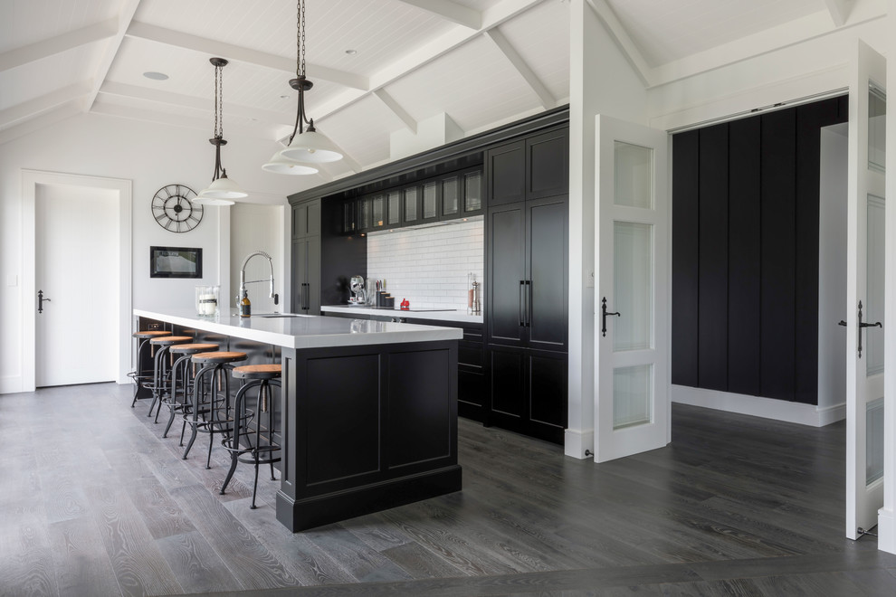 Mid-sized traditional galley eat-in kitchen in Auckland with dark hardwood floors, grey floor, a drop-in sink, recessed-panel cabinets, black cabinets, granite benchtops, white splashback, ceramic splashback, black appliances and with island.