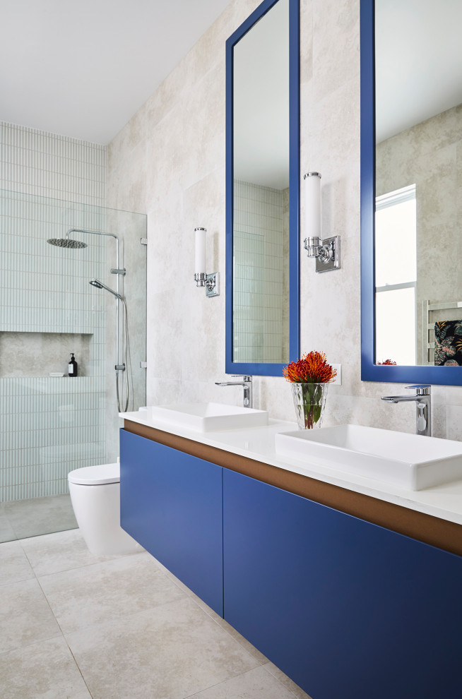 Стильный дизайн: большая ванная комната в современном стиле с синими фасадами, открытым душем, инсталляцией, бежевой плиткой, керамогранитной плиткой, бежевыми стенами, полом из керамической плитки, накладной раковиной, столешницей из искусственного кварца, бежевым полом, нишей, тумбой под две раковины и подвесной тумбой - последний тренд