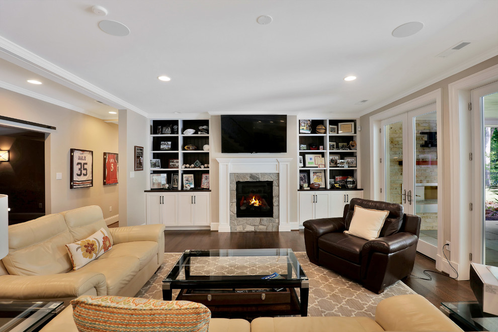 Inspiration for a large transitional enclosed family room in Richmond with a library, beige walls, medium hardwood floors, a standard fireplace, a stone fireplace surround and a wall-mounted tv.
