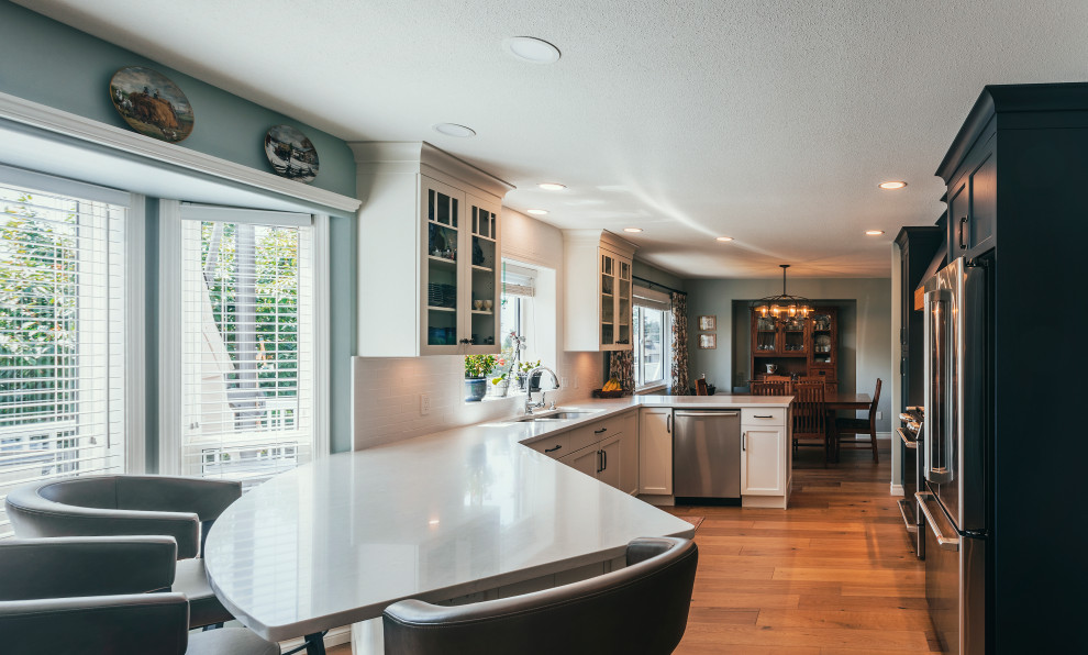 Large minimalist galley light wood floor and brown floor open concept kitchen photo in Vancouver with an undermount sink, shaker cabinets, white cabinets, quartz countertops, white backsplash, subway tile backsplash, stainless steel appliances and white countertops