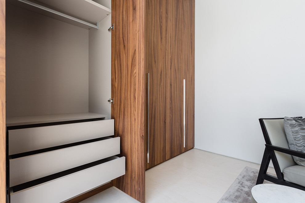 Design ideas for a large contemporary gender-neutral built-in wardrobe in Los Angeles with flat-panel cabinets, light wood cabinets, ceramic floors and beige floor.