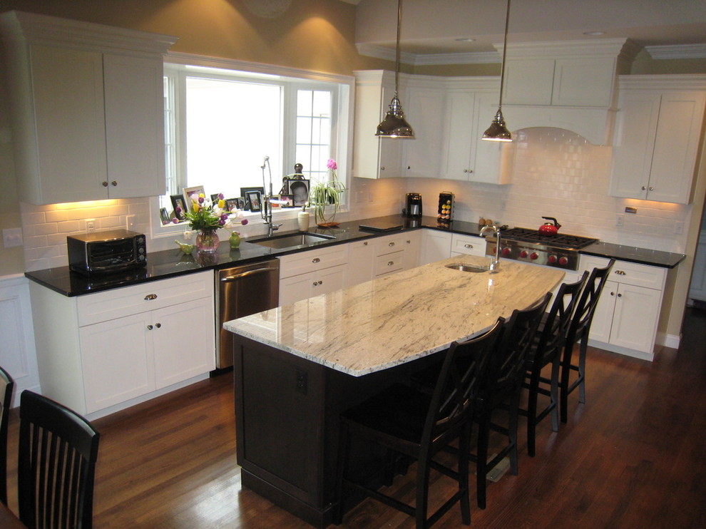 Inspiration for a mid-sized transitional l-shaped medium tone wood floor and brown floor open concept kitchen remodel in Providence with granite countertops, an undermount sink, recessed-panel cabinets, white cabinets, white backsplash, ceramic backsplash, stainless steel appliances, an island and beige countertops