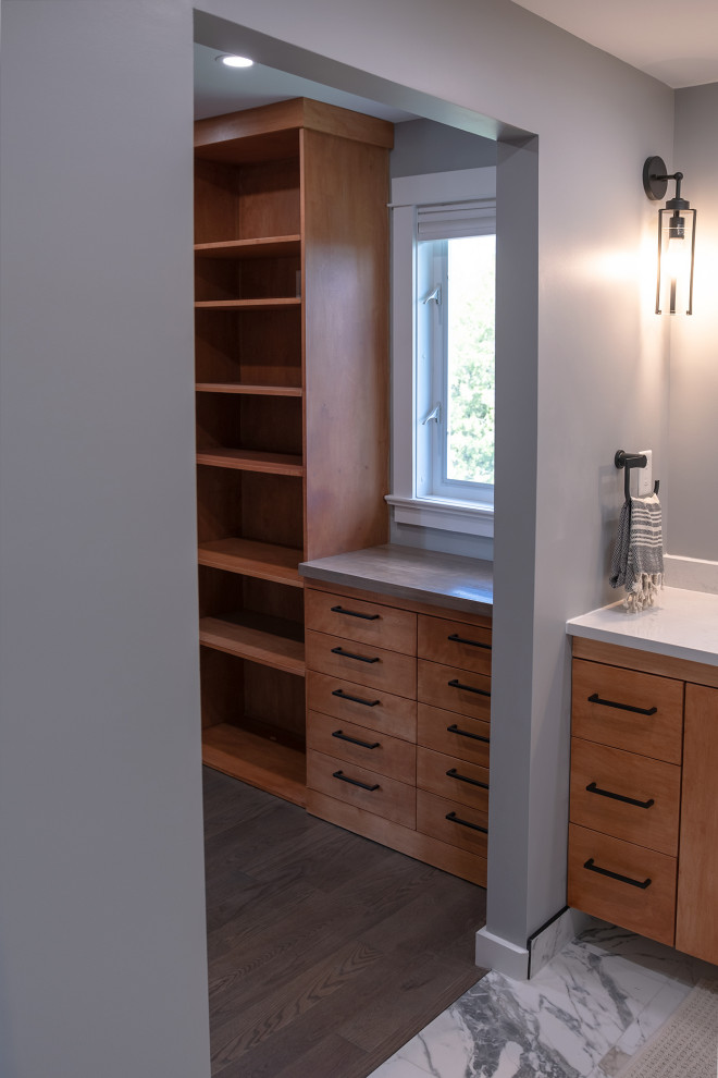 Photo of a contemporary gender neutral walk-in wardrobe in Ottawa with flat-panel cabinets, medium wood cabinets, laminate floors and brown floors.