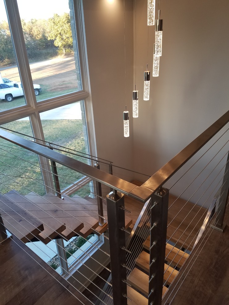 Lake House Dream - In progress pictures of floating staircase. Front focal stairway that provides access from a large open expansive downstairs living to the upstairs bedrooms, deck and game room. HSS Structural steel support hidden in walls with solid white oak treads and stainless steel handrails and cable. LED lights were installed in the nosing of the stairs. Bona-Waterborne Traffic Naturale finish used on stairs for natural color, matte finish level and seamless touch-up on repairs.