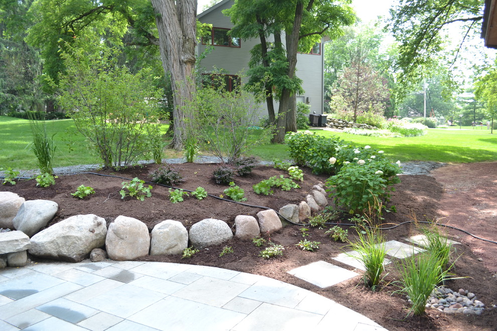 Inspiration for a mid-sized rustic backyard stone landscaping in Milwaukee.