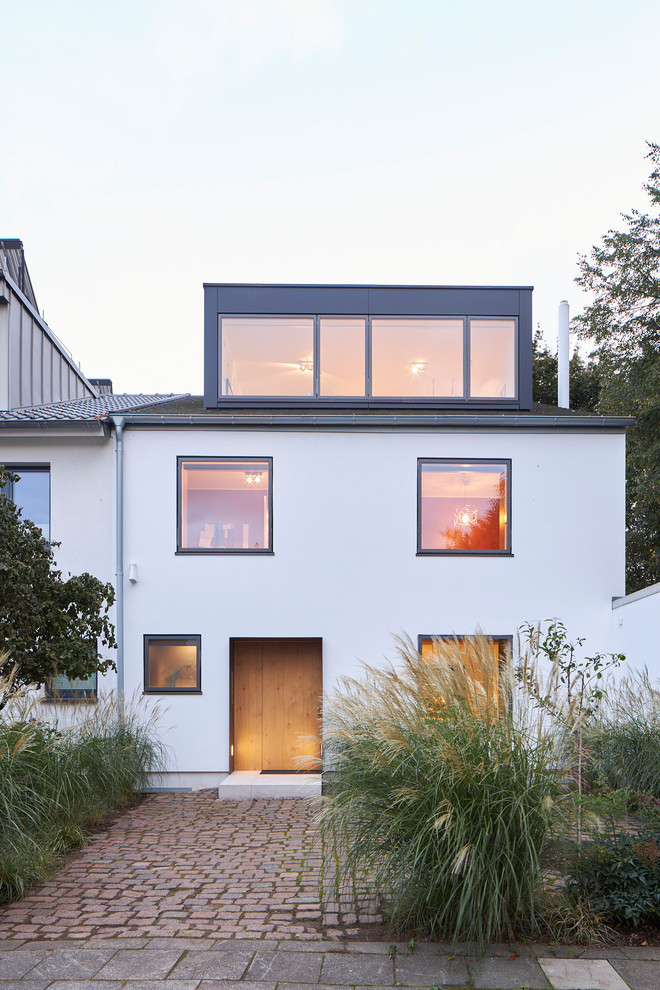 Mid-sized modern stucco white townhouse exterior in Cologne with a gable roof and a tile roof.