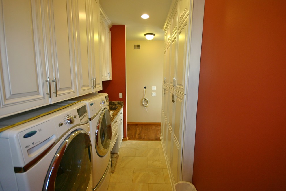 Small modern single-wall utility room in Milwaukee with an undermount sink, raised-panel cabinets, white cabinets, granite benchtops, beige splashback, stone tile splashback, porcelain floors, red walls and a side-by-side washer and dryer.