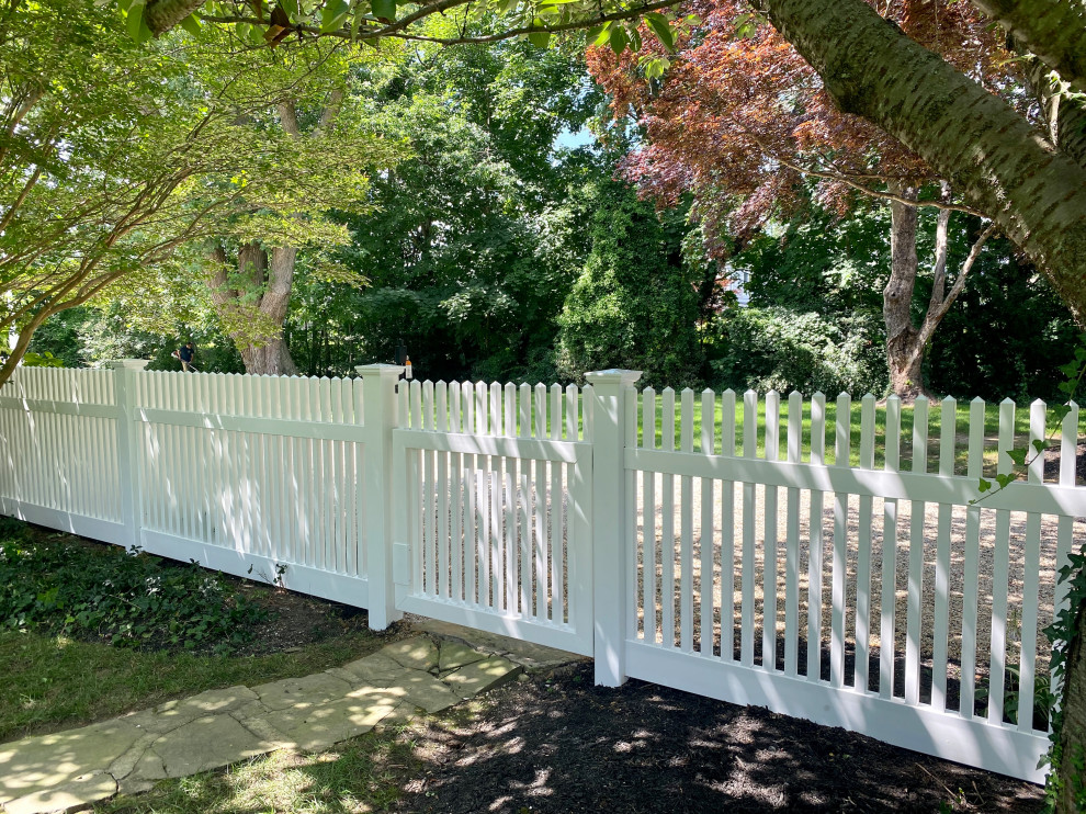 Photo of a traditional garden in New York with with a gate and a vinyl fence.