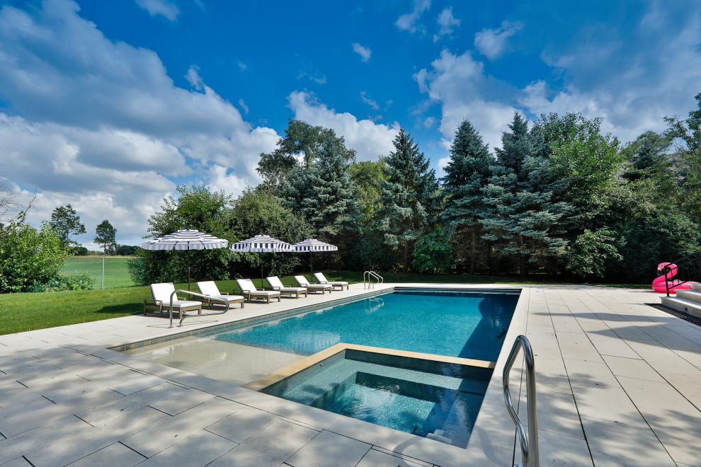 Mid-sized traditional backyard rectangular lap pool in Chicago with a hot tub and natural stone pavers.