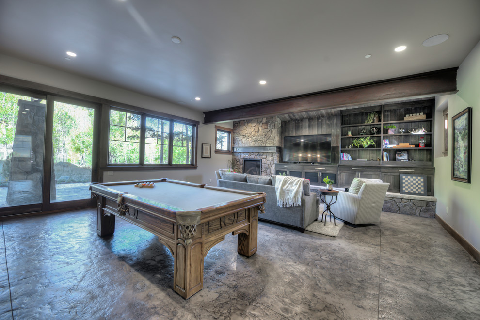 Inspiration for a large transitional open concept family room with a game room, concrete floors, a hanging fireplace, a stone fireplace surround, a freestanding tv and multi-coloured floor.