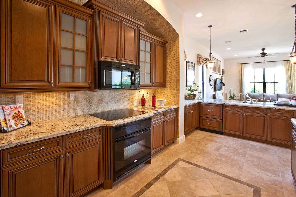 This is an example of a large traditional open plan kitchen in Miami with an undermount sink, raised-panel cabinets, medium wood cabinets, granite benchtops, beige splashback, mosaic tile splashback, black appliances, ceramic floors and a peninsula.