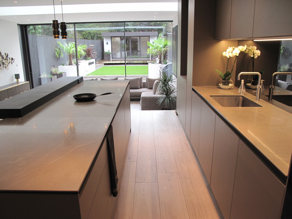 Design ideas for a large modern galley open plan kitchen in London with an integrated sink, recessed-panel cabinets, grey cabinets, tile benchtops, grey splashback, glass tile splashback, coloured appliances, porcelain floors, with island, brown floor, green benchtop and coffered.