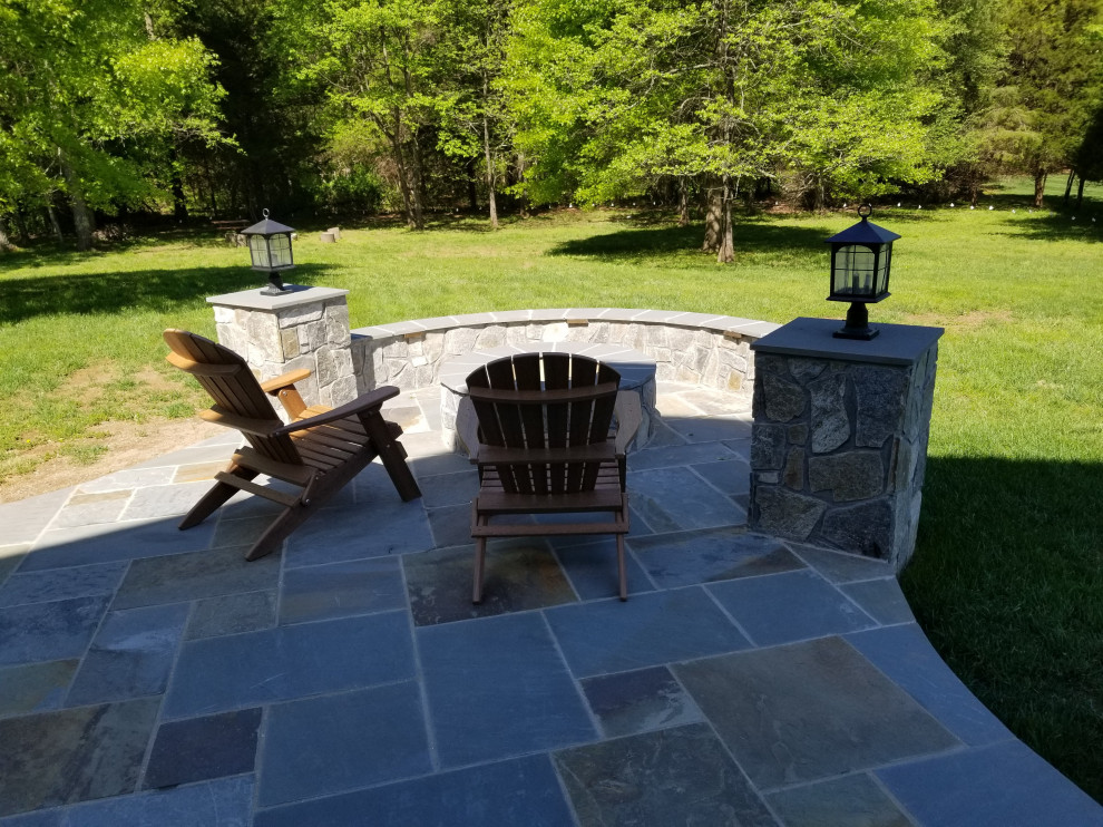 Patio - large rustic backyard stone patio idea with a fire pit