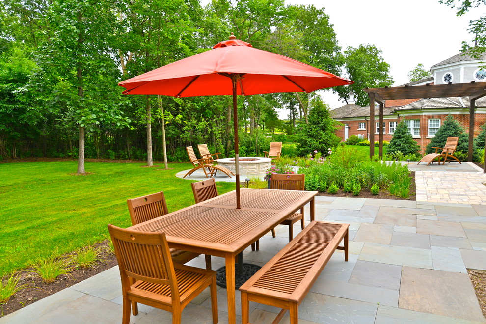Large traditional backyard patio in Chicago with a fire feature, a pergola and natural stone pavers.