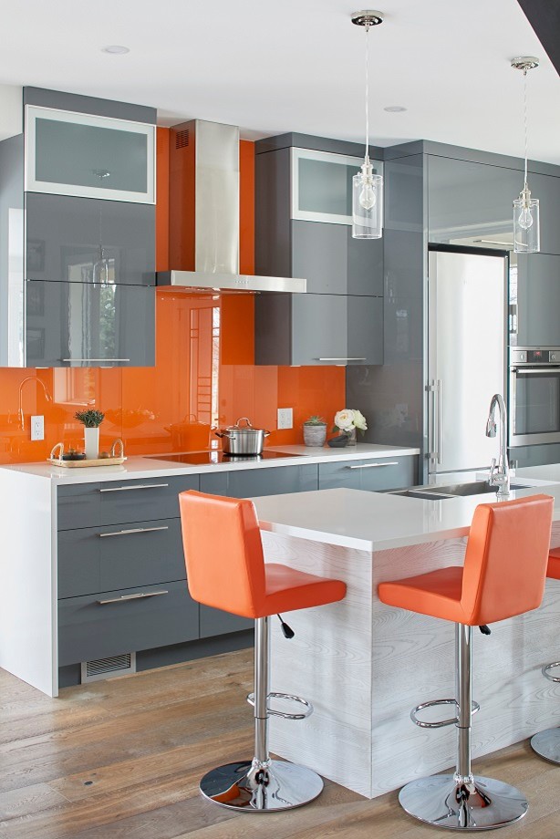 Design ideas for a mid-sized modern single-wall eat-in kitchen in Toronto with a farmhouse sink, flat-panel cabinets, grey cabinets, orange splashback, glass tile splashback, stainless steel appliances, dark hardwood floors, with island and brown floor.