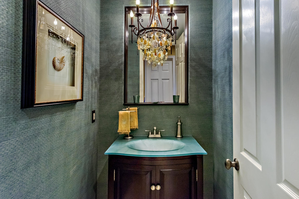 Photo of a small mediterranean powder room in Orange County with glass benchtops, furniture-like cabinets, dark wood cabinets, grey walls and an integrated sink.