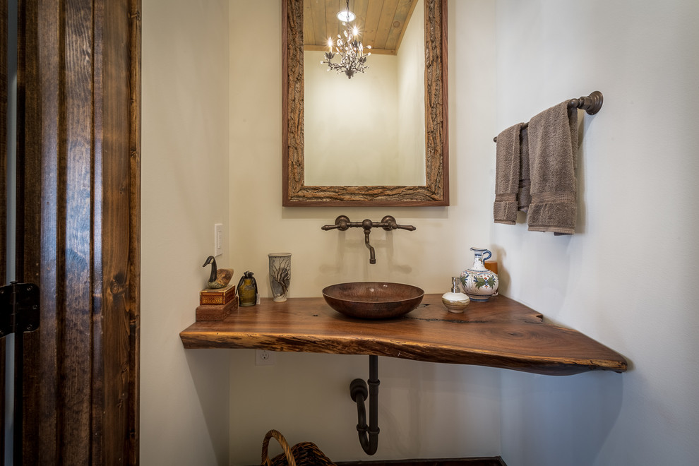 This is an example of an expansive country bathroom in Charlotte with a vessel sink, wood benchtops, a two-piece toilet, stone tile, white walls, medium hardwood floors and brown benchtops.