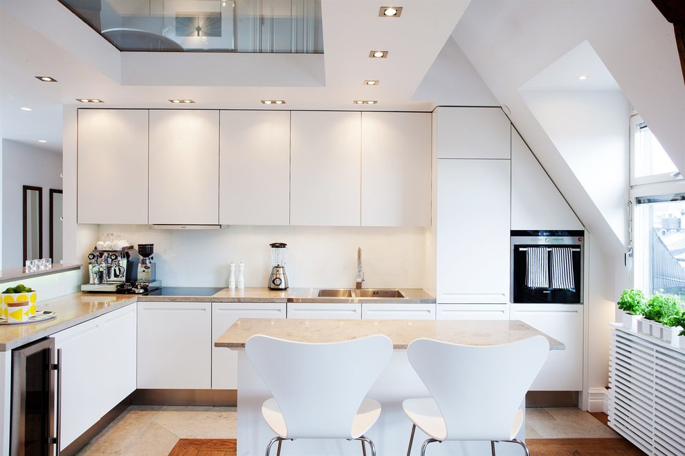 Inspiration for a large scandinavian l-shaped eat-in kitchen in Stockholm with a double-bowl sink, flat-panel cabinets, white cabinets, white splashback, stainless steel appliances, with island, granite benchtops and ceramic floors.