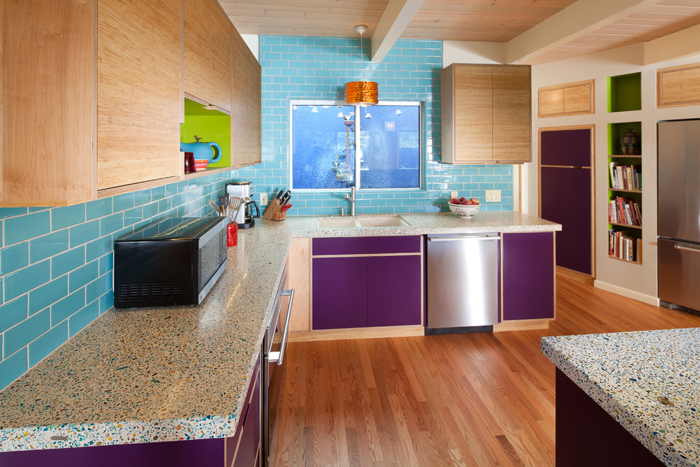 Photo of a mid-sized eclectic u-shaped eat-in kitchen in San Luis Obispo with stainless steel appliances, flat-panel cabinets, subway tile splashback, light wood cabinets, an undermount sink, blue splashback, medium hardwood floors, a peninsula, brown floor, recycled glass benchtops and multi-coloured benchtop.