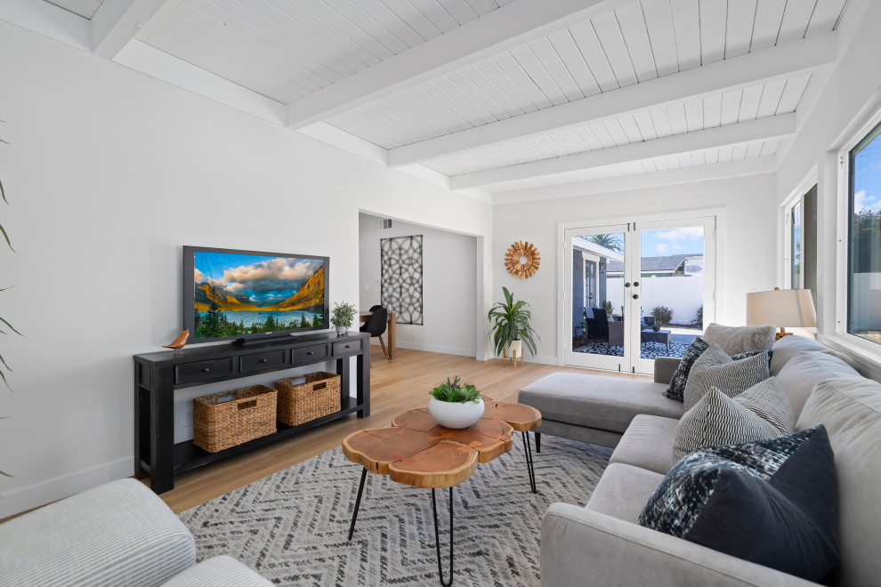 Imagen de sala de estar retro con paredes blancas, suelo laminado, televisor independiente y vigas vistas
