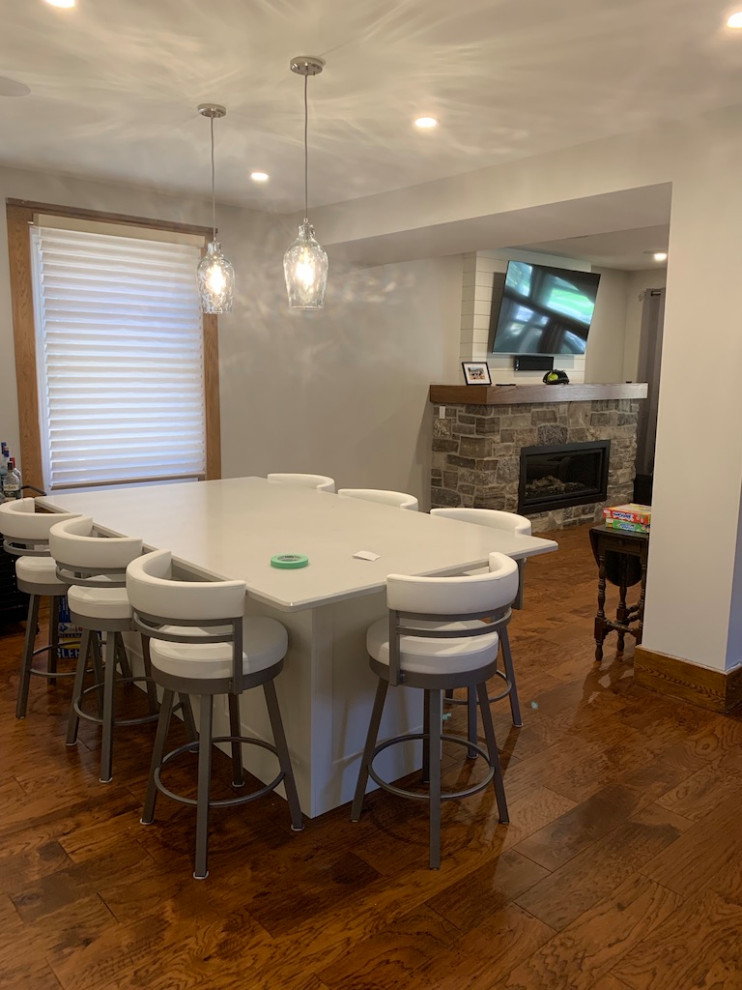 Open concept kitchen - small transitional galley medium tone wood floor open concept kitchen idea in Toronto with shaker cabinets, white cabinets, solid surface countertops, an island and white countertops