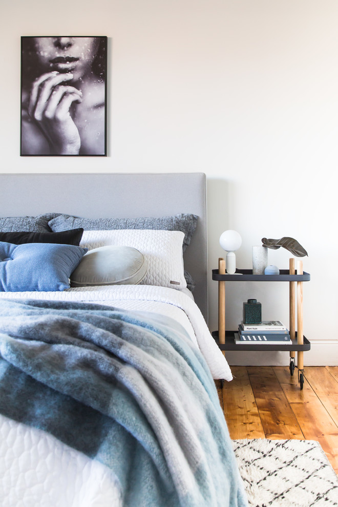 Design ideas for a contemporary guest bedroom in Melbourne with white walls, light hardwood floors and brown floor.