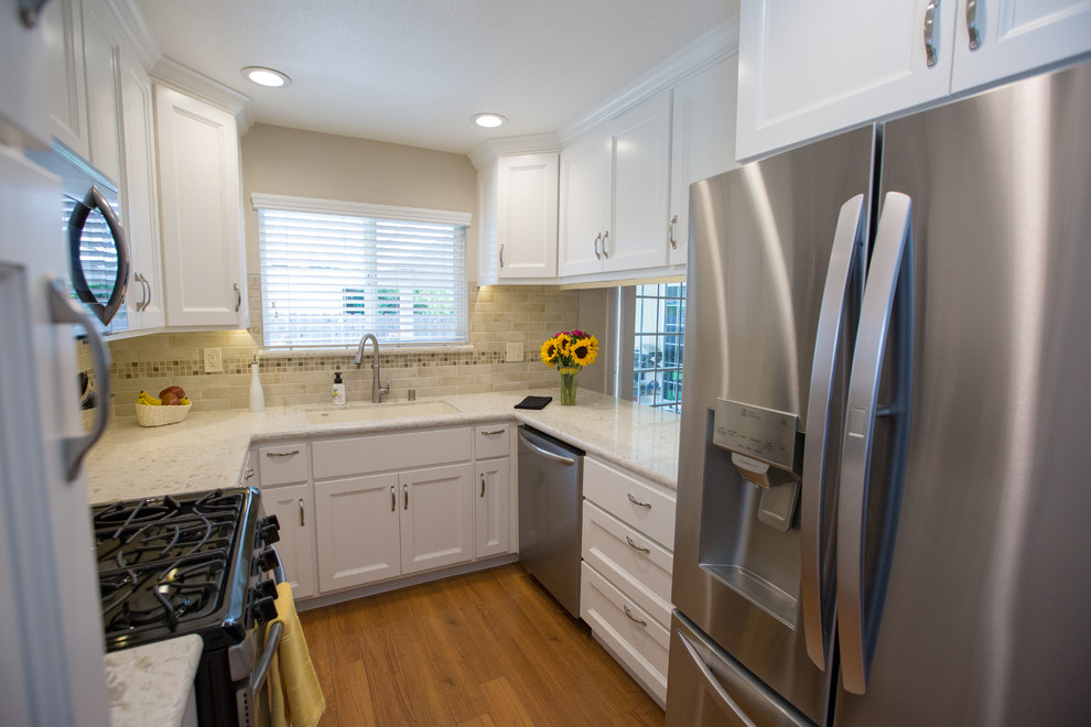This is an example of a traditional u-shaped separate kitchen in Sacramento with white cabinets, quartz benchtops, beige splashback, stainless steel appliances and white benchtop.