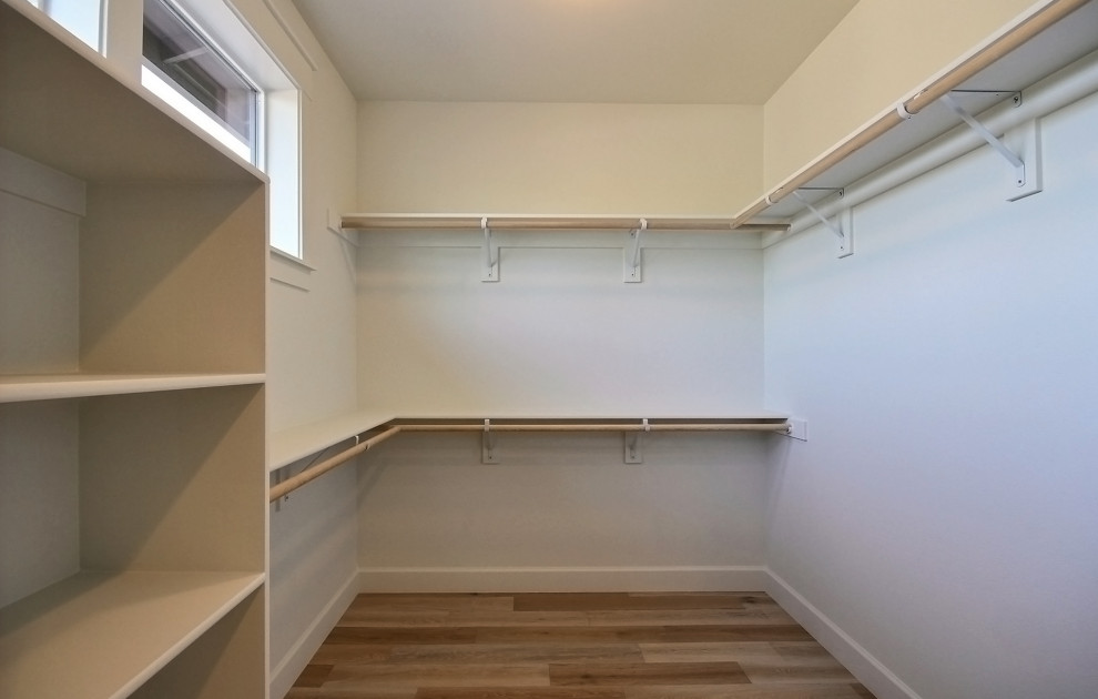 Inspiration for an expansive modern gender neutral walk-in wardrobe in Portland with open cabinets, white cabinets, light hardwood flooring and brown floors.