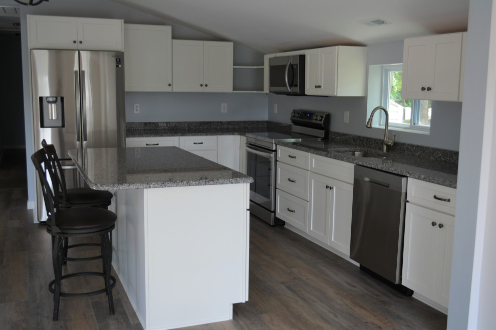 Klassisk inredning av ett litet grå grått u-kök, med en undermonterad diskho, släta luckor, vita skåp, granitbänkskiva, blått stänkskydd, rostfria vitvaror och en köksö