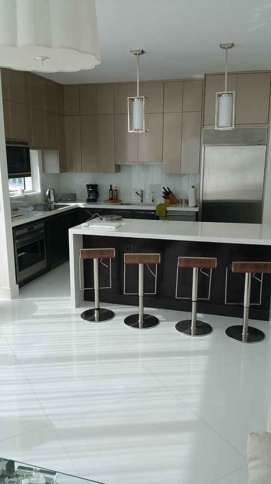 Large modern l-shaped eat-in kitchen in Miami with an undermount sink, flat-panel cabinets, medium wood cabinets, quartzite benchtops, white splashback, glass sheet splashback, stainless steel appliances, porcelain floors and with island.