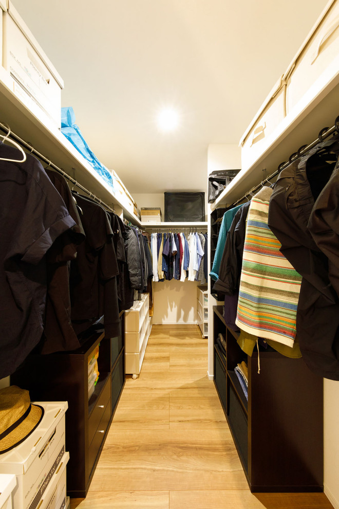 Photo of a mid-sized industrial gender-neutral walk-in wardrobe in Tokyo Suburbs with open cabinets, white cabinets, light hardwood floors, beige floor and wallpaper.
