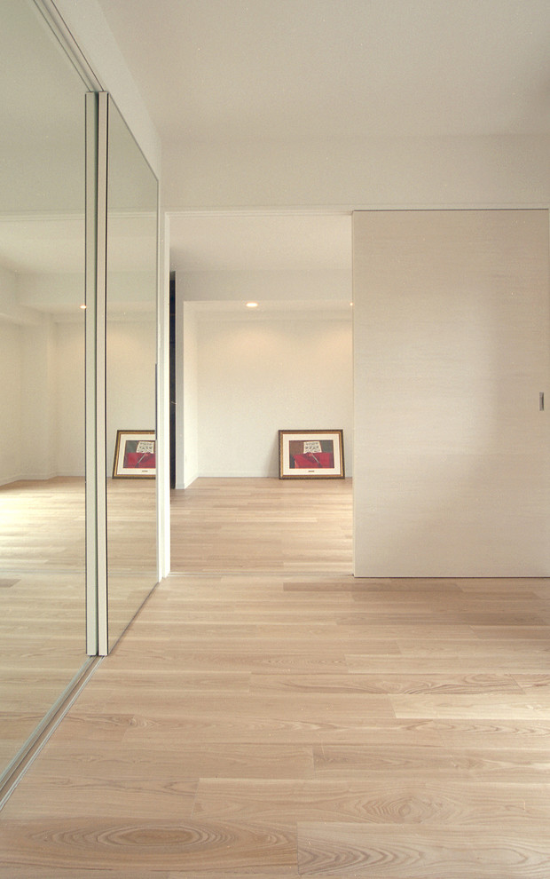 Inspiration pour une petite chambre parentale minimaliste avec un mur blanc, un sol en contreplaqué, aucune cheminée et un sol marron.