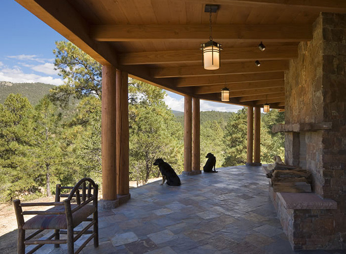 This is an example of a mid-sized country backyard verandah in Albuquerque with natural stone pavers and a roof extension.